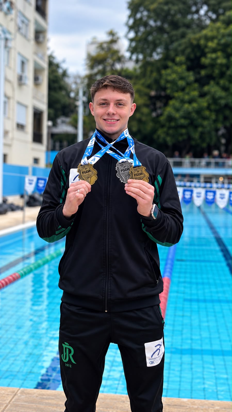 Arthur Tomazzoni com medalhas diante da piscina